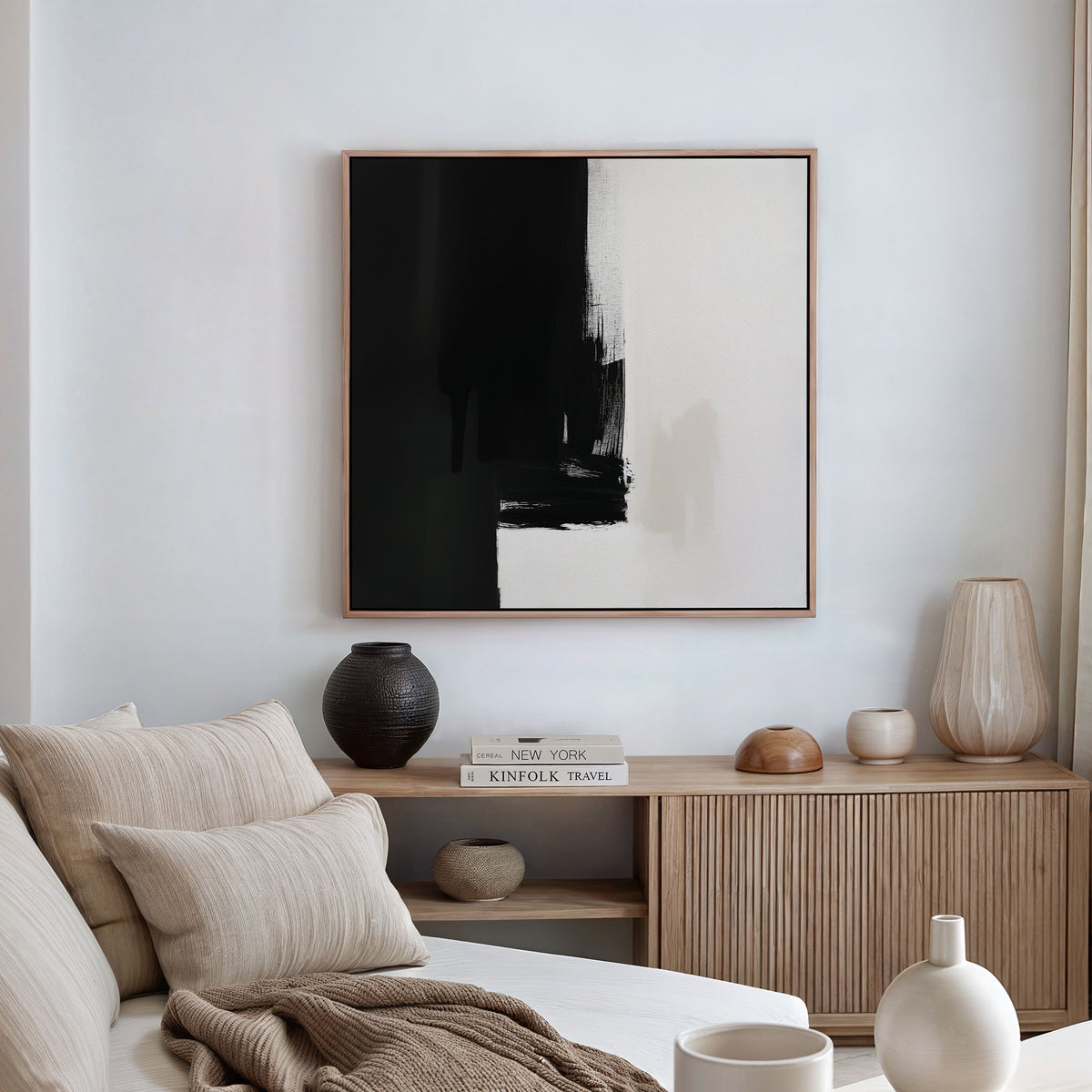 A minimal, modern living room with a beige sofa, striped cushions, wooden sideboard, neutral decor accents, and the striking "Ink Divide Canvas Art - Square" inspired by Nordic Park displayed on the white wall.