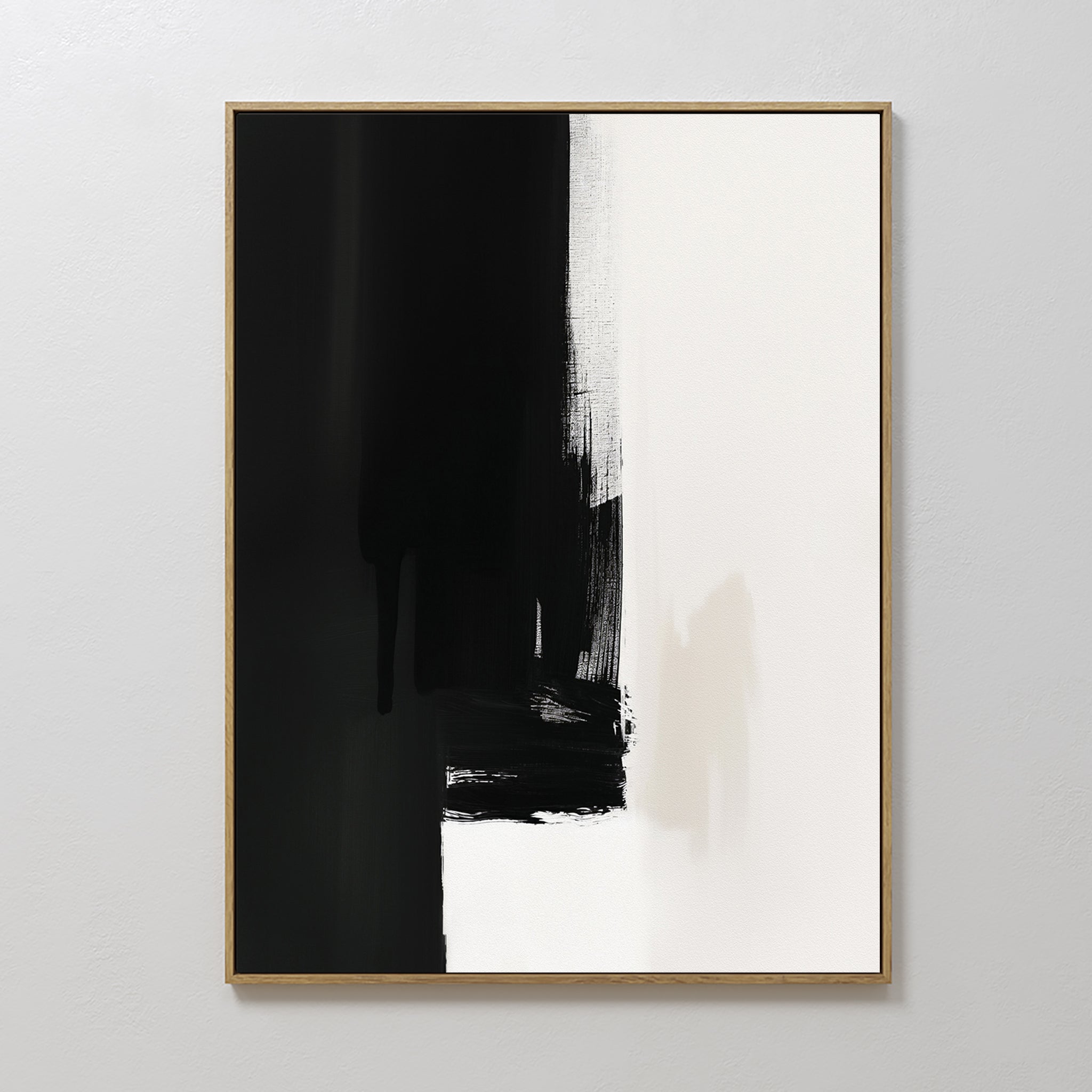 The Ink Divide Canvas Art - Vertical features bold black brushstrokes blending into white with textured, uneven edges, epitomizing minimalist wall art. Hung on a plain white wall, its striking abstract design makes a modern statement.