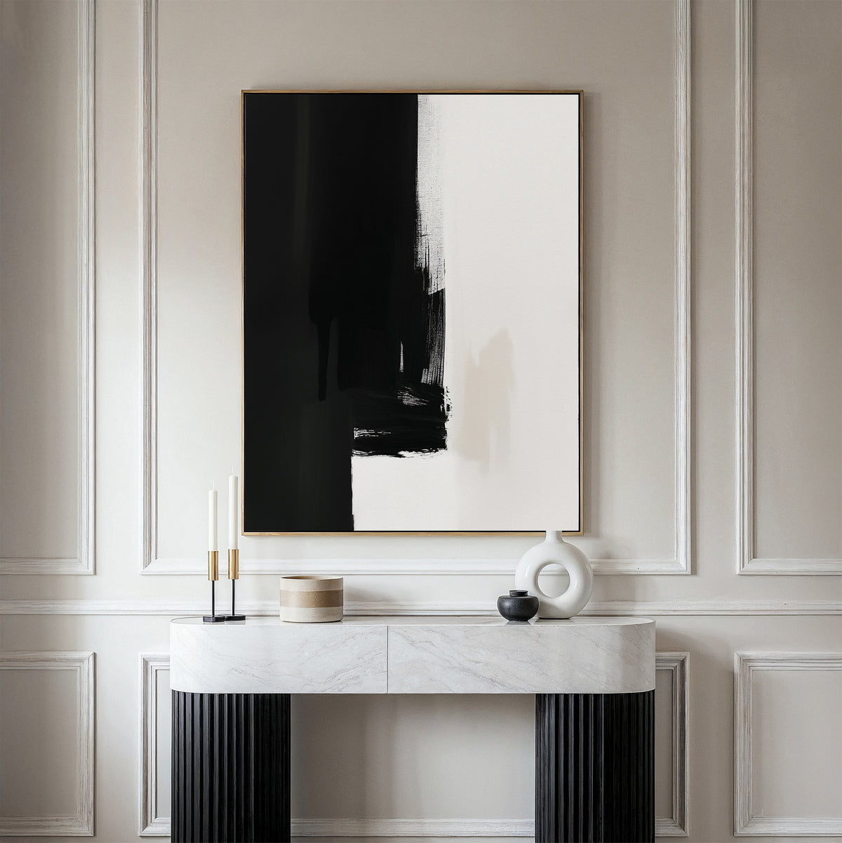 Minimalist interior featuring the Ink Divide Canvas Art - Vertical, a large abstract black and white painting on a cream-paneled wall, paired with a marble console table and decorative objects for a refined, modern atmosphere.