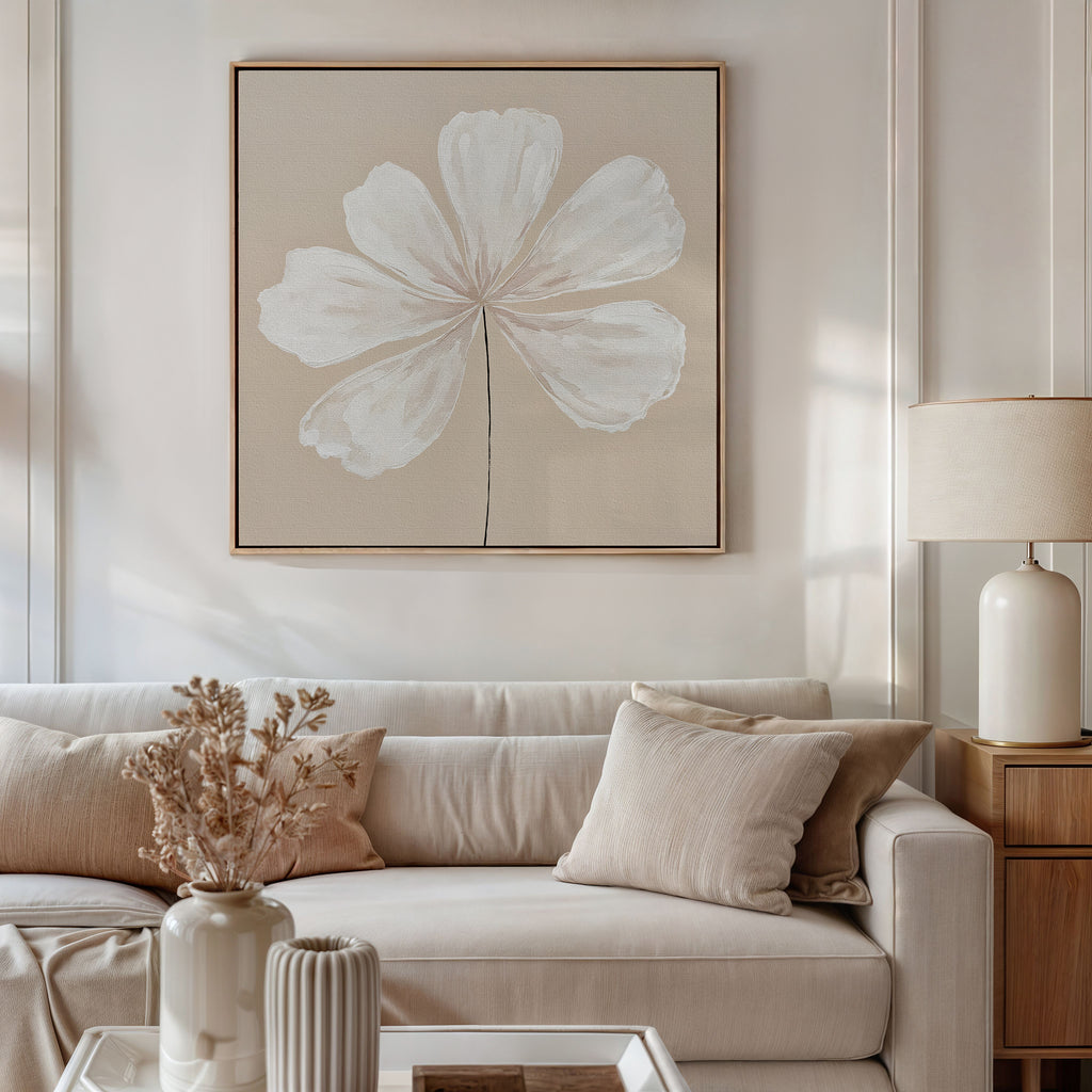 A neutral-toned living room features a beige sofa with matching cushions, a side table with a ceramic lamp, and the Ivory Bloom Canvas Art - Square as striking botanical wall decor. A vase of dried flowers accents the coffee table for perfect neutral style.