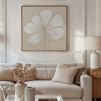 A neutral-toned living room features a beige sofa with matching cushions, a side table with a ceramic lamp, and the Ivory Bloom Canvas Art - Square as striking botanical wall decor. A vase of dried flowers accents the coffee table for perfect neutral style.