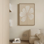 Minimalist living room with a beige wall, cream sofa, shelves of books, and the Ivory Bloom Canvas Art - Vertical: an elegant print featuring a white flower with delicate petals.