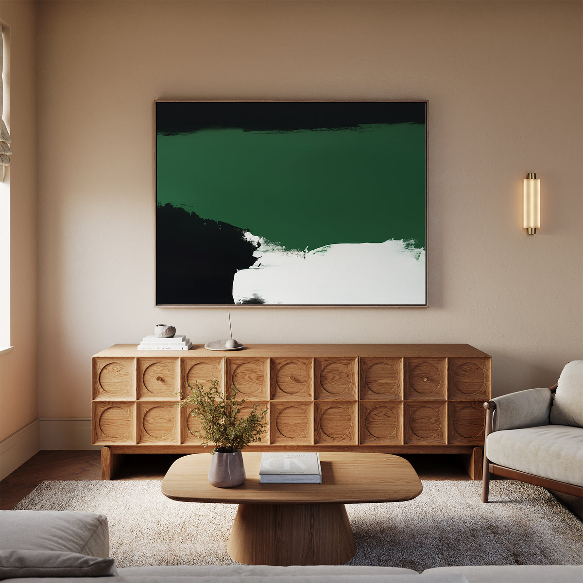 A modern living room with a light sofa, wooden coffee table, and a sideboard with circular patterns. Above the sideboard hangs the Jade Depths Canvas Art - Horizontal in emerald green abstract style. A small wall light is on the right.