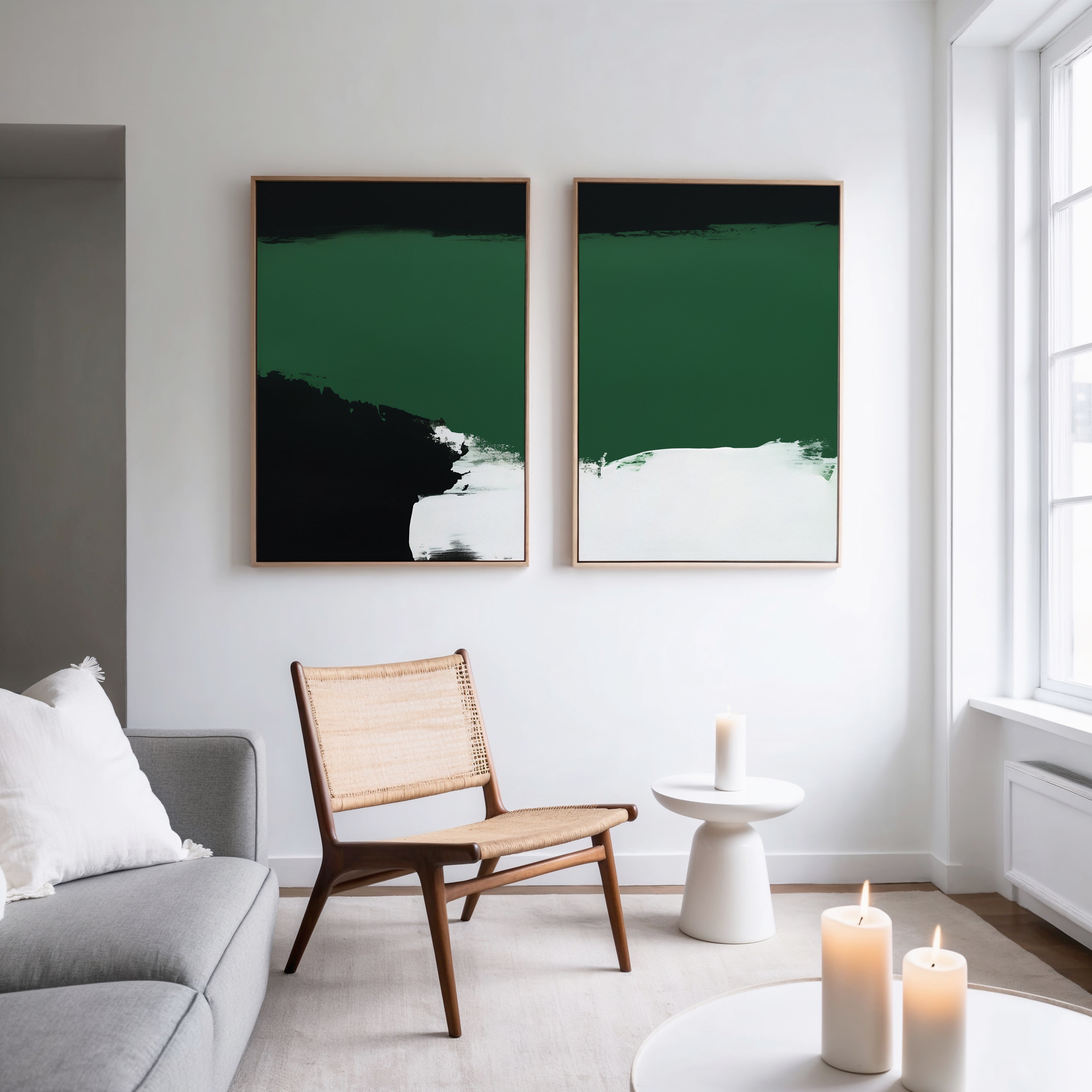 A modern, minimalist living room with a gray sofa, woven chair, and white tables is styled with candles and Jade Depths - Set Of 2 wall art—bringing striking contemporary print accents to the space.