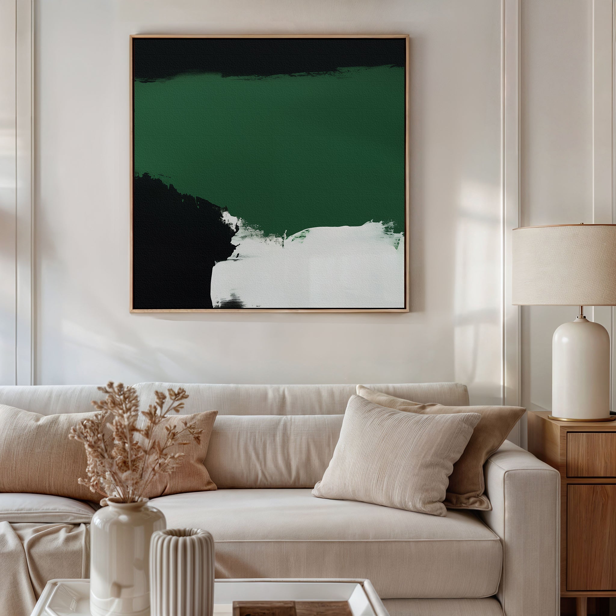 A modern living room features a beige sofa, cream pillows, a round beige lamp on a wooden side table, dried flowers in a vase, and the striking Jade Depths Canvas Art - Square as emerald green wall art for contemporary flair.