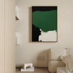 A minimal living room features a beige sofa, light wood shelves with books, and a modern touch— the Jade Depths Canvas Art - Vertical in emerald green, black, and white—plus a small geometric decor piece on the floor.