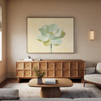 A modern living room with light walls features a wooden sideboard, the Jade Reflection Canvas Art - Horizontal above it, a round coffee table with a vase, and a beige armchair on a soft rug. Warm lighting enhances the cozy atmosphere.