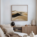 A cozy, modern living room with a textured sofa, decorative cushions, and a wooden sideboard is accented by the Dune Waves Abstract Canvas Art, featuring a minimalist desert landscape in beige, brown, and black tones.
