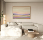 A modern living room with a light beige sectional sofa, a light wood coffee table, and the Lavender Valley Canvas Art - Horizontal on the wall. Soft natural light filters through sheer curtains, and a tall plant sits in the corner.