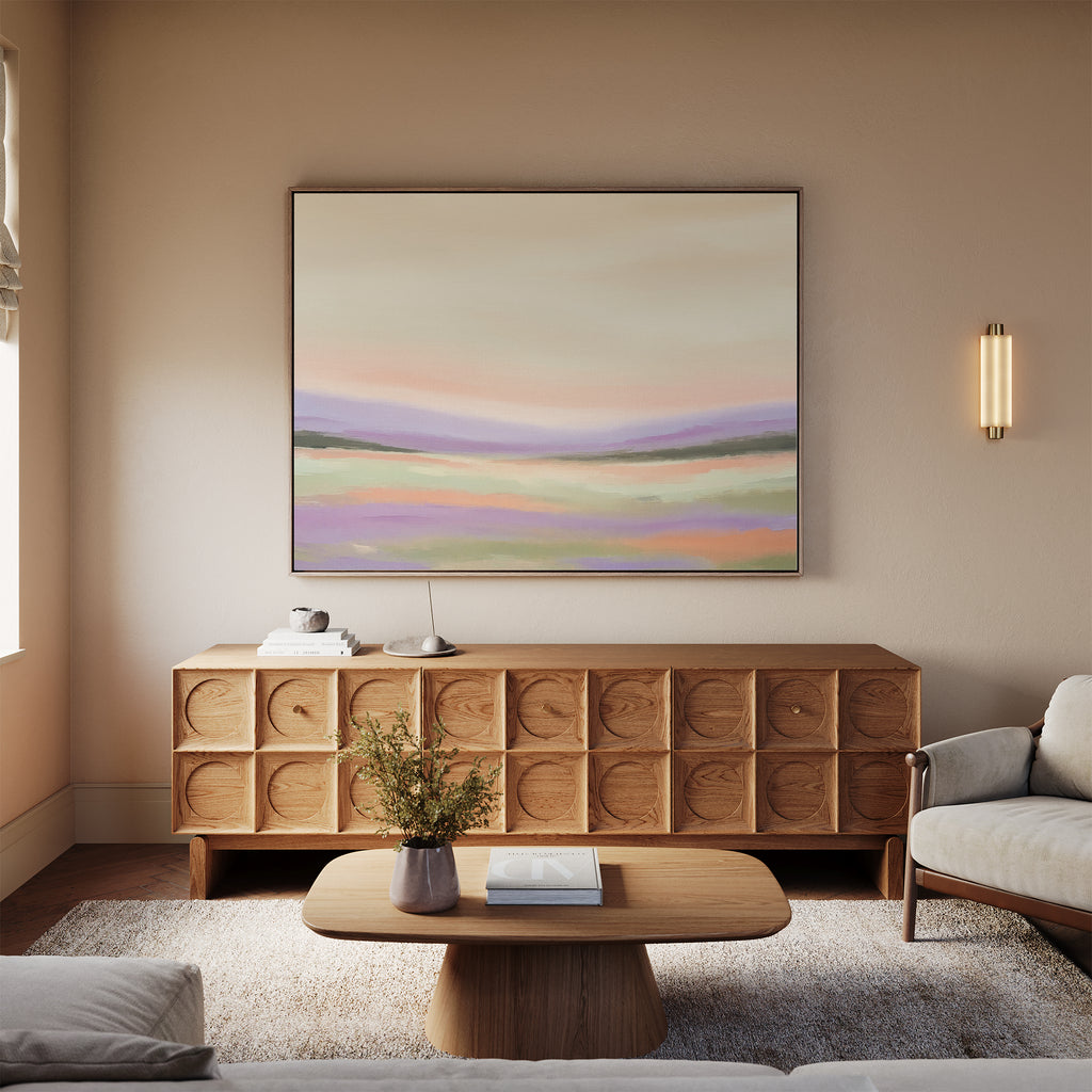 A modern living room features a wooden sideboard with books and flowers, a beige sofa, and soft neutral tones. Above hangs the Lavender Valley Canvas Art - Horizontal, adding serene Nordic-inspired flair to the space.