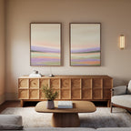 A cozy living room with a modern sofa, geometric wooden sideboard, and serene "Lavender Valley - Set Of 2" wall art above. A light wood coffee table holds a vase with greenery as soft lighting creates a warm, inviting atmosphere.