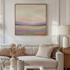 A modern living room features a beige sofa, neutral pillows, a light lamp, and vases with dried flowers on the table. Above the sofa hangs the Lavender Valley Canvas Art - Square, adding a serene and tranquil touch to the space.