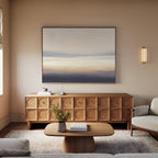 A modern living room displays a wooden sideboard, minimalist coffee table, light gray sofa, and a vase with flowers. Above the sideboard, Layered Dusk Canvas Art - Horizontal adds calming warmth with neutral abstract tones.