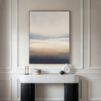 A minimalist hallway showcases a marble console table with black legs, candles, a round vase, and a lidded container. Above the paneled wall hangs the Layered Dusk Canvas Art - Vertical as striking abstract wall art.