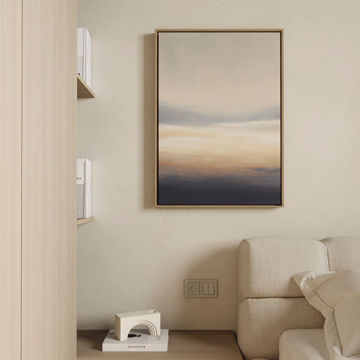 A modern living room corner with a beige sofa, light wood shelves with books, a small abstract sculpture, and Layered Dusk Canvas Art - Vertical featuring soft beige, blue, and orange tones hanging on the wall.