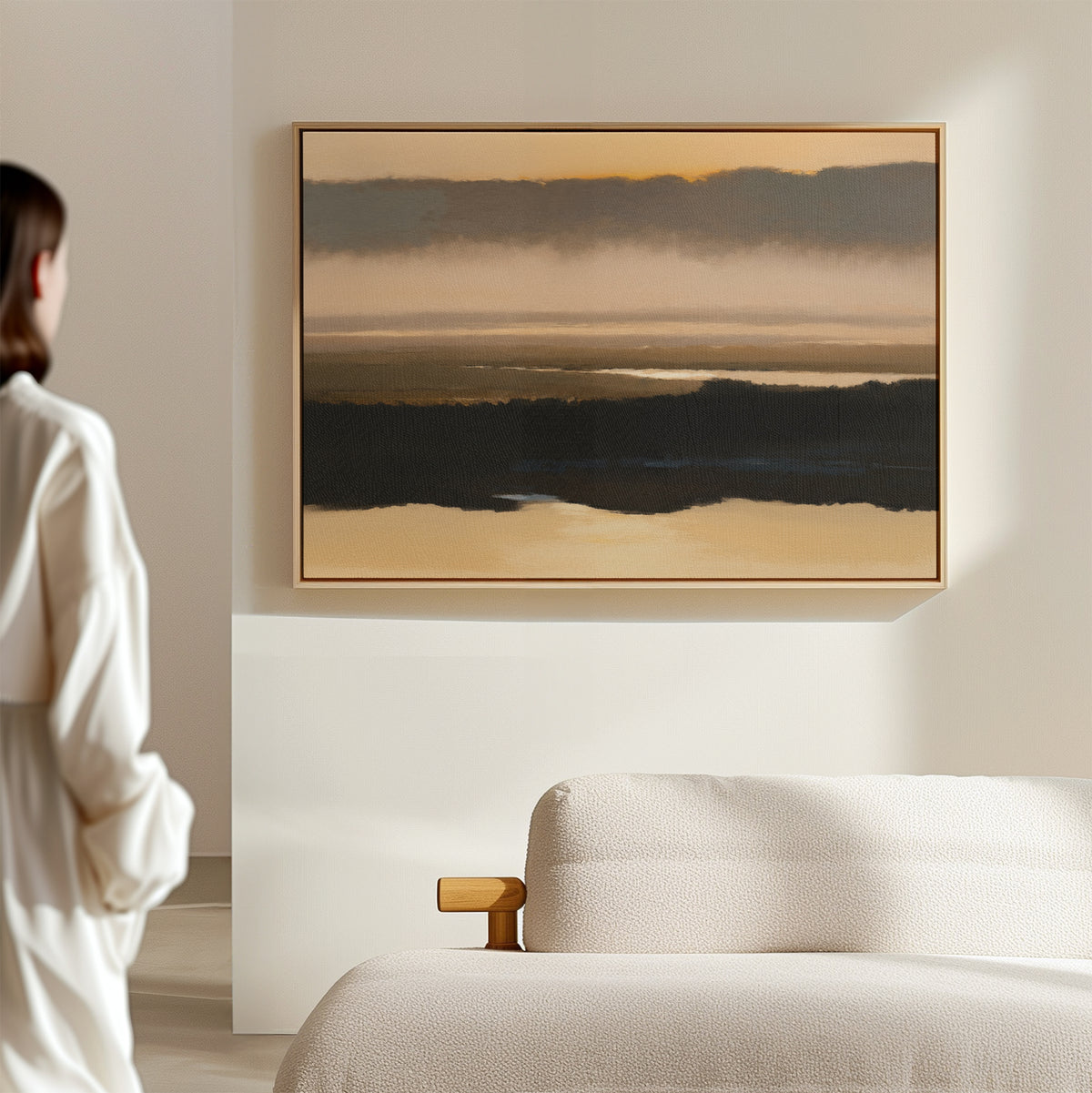 A person in a white shirt stands in a modern, minimalistic room, admiring the Layered Valley Dawn Canvas Art - Horizontal hanging above a textured light-colored sofa on a beige wall.