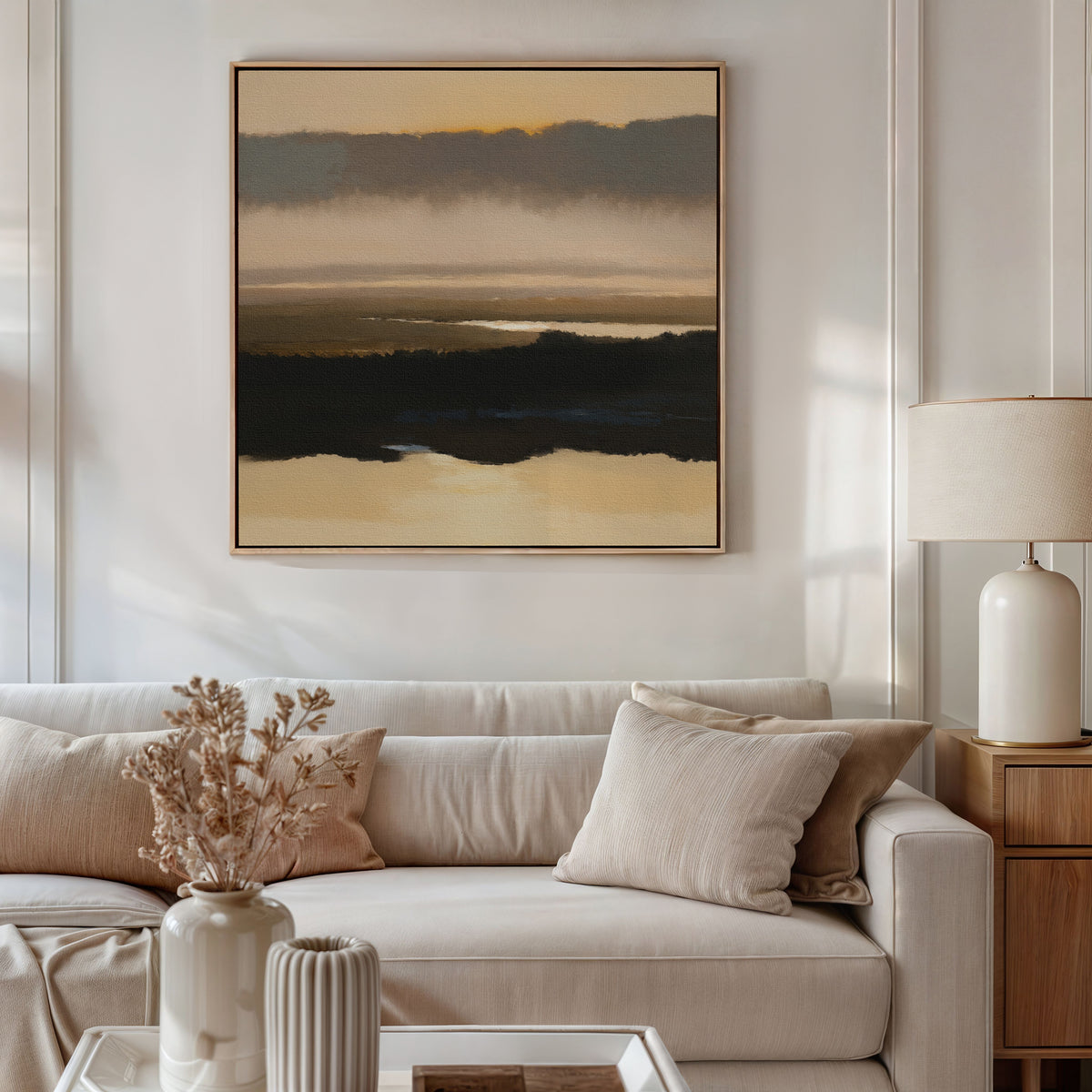 A neutral-toned living room features a beige sofa, cream and tan cushions, a wooden side table with a lamp, dried flowers in a vase, and the Layered Valley Dawn Canvas Art - Square hanging above the sofa for a serene touch.