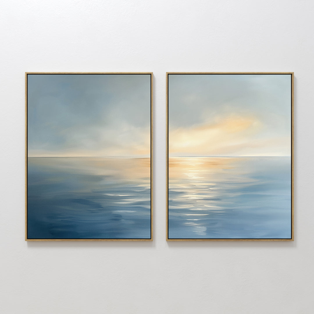 The "Luminous Calm - Set of 2" features framed abstract paintings of a serene sea and sunset in soft blue, yellow, and orange tones with gentle reflections, creating a tranquil atmosphere on any white wall.