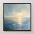 The Luminous Calm Canvas Art - Square features a serene seascape with soft blue water and golden-orange hues, capturing sunlight breaking through clouds at sunrise or sunset. This framed print brings tranquil coastal beauty to your space.