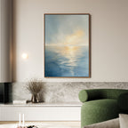 A modern living room features a green sofa, a marble ledge with a vase of dried branches, and the Luminous Calm Canvas Art - Vertical displaying a serene sea scene in soft coastal hues on the wall.