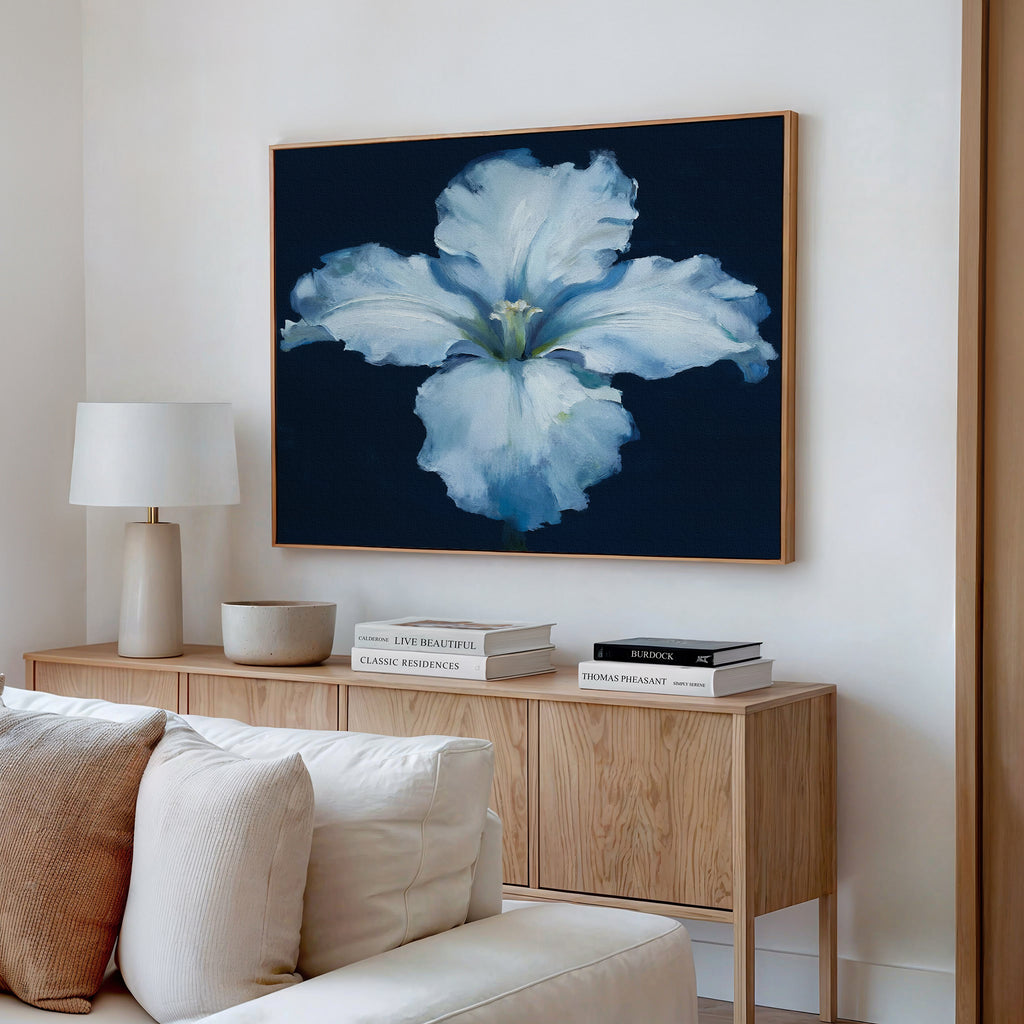 A modern living room features a wooden sideboard with stacked books, a ceramic bowl, a white table lamp, and the Luminous Iris Canvas Art - Horizontal displayed above the sideboard.