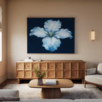 A cozy living room features a wooden coffee table, beige rug, modern light wood sideboard, and the "Luminous Iris Canvas Art - Horizontal" in blue and white above the sideboard. A beige sofa and soft lighting complete the scene.