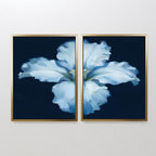 The "Luminous Iris - Set of 2" features diptych wall art with soft blue iris petals on a dark blue backdrop, split across two gold-framed canvases to create a serene Nordic vibe, perfect for display on a white wall.