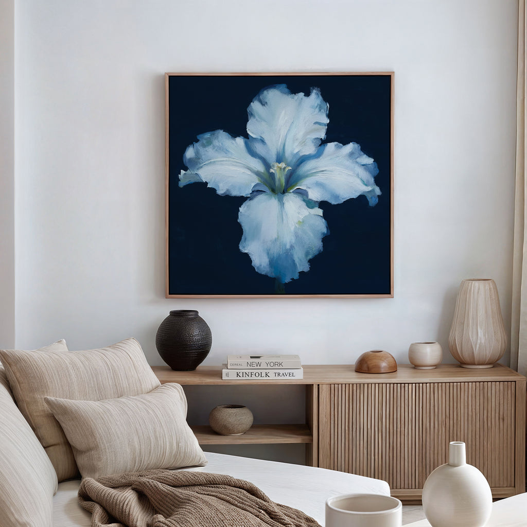 A modern living room with a neutral sofa, light wood sideboard, decorative vases, and the Luminous Iris Canvas Art - Square—a striking white blossom on deep blue—brings an artistic Nordic Park vibe to the space.