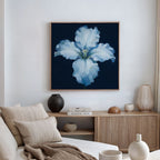 A modern living room with a neutral sofa, light wood sideboard, decorative vases, and the Luminous Iris Canvas Art - Square—a striking white blossom on deep blue—brings an artistic Nordic Park vibe to the space.