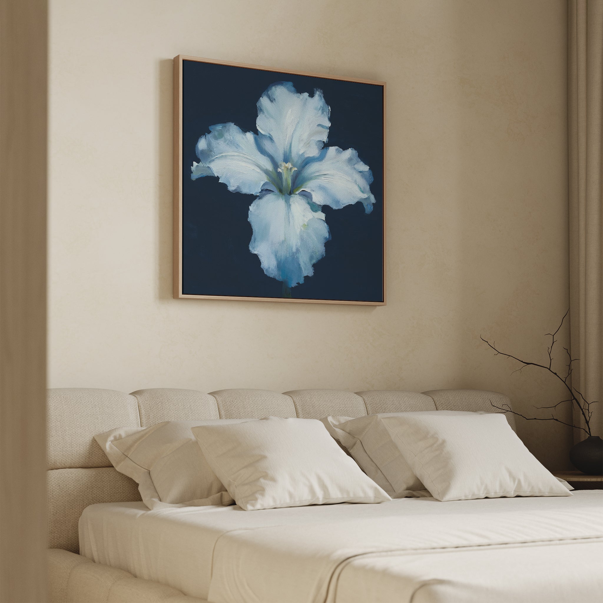 A beige bedroom with a neatly made bed, white pillows, and the Luminous Iris Canvas Art - Square in a gold frame above the headboard. A bare branch accents a side table by the window.