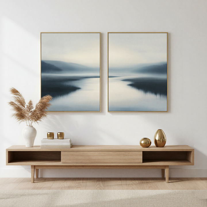 Minimalist living room with a light wood console table, decorative vases, pampas grass, books, and the Peaceful Waters Set of 2 calm landscape wall art featuring misty blue and white lakescapes for tranquil decor.
