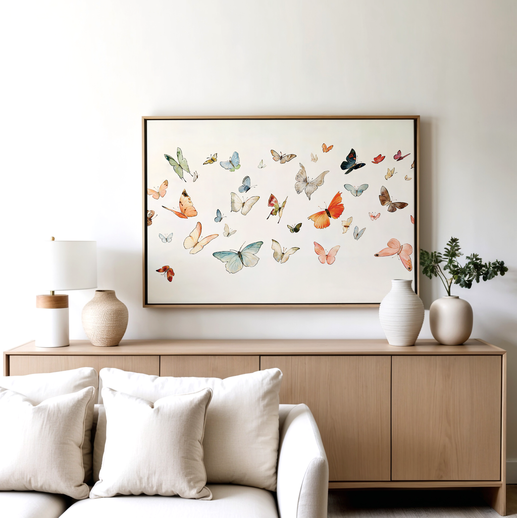 A modern living room featuring a light wood sideboard, white vases, a table lamp, and the Fluttering Dreams Abstract Canvas Art above a white sofa with neutral pillows creates striking minimalist wall decor.