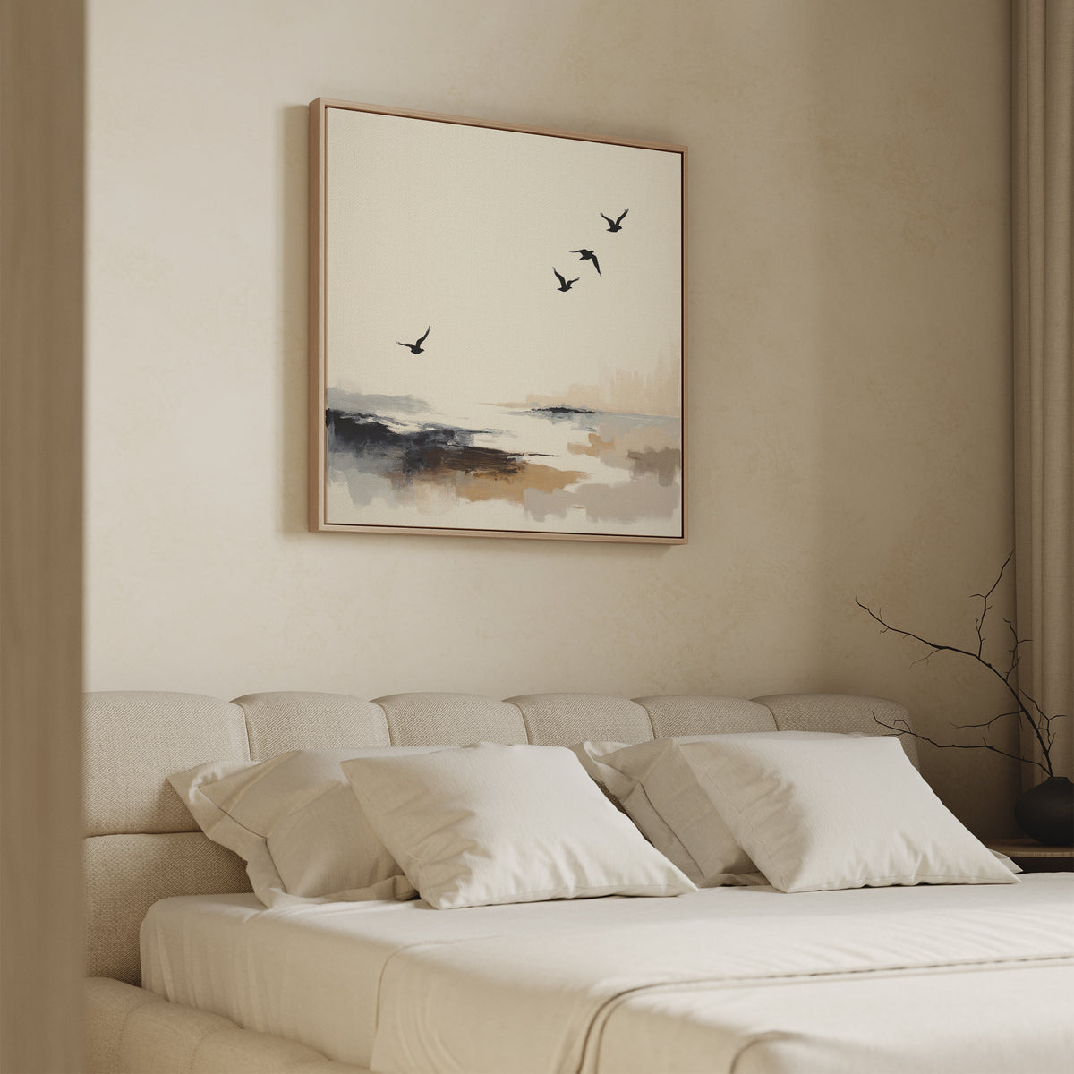 A beige bedroom with a cushioned headboard, white bedding, and four pillows. Above the bed hangs the Maritime Flight Canvas Art - Square, depicting flying birds in coastal tones. A vase with branches sits on a bedside table.