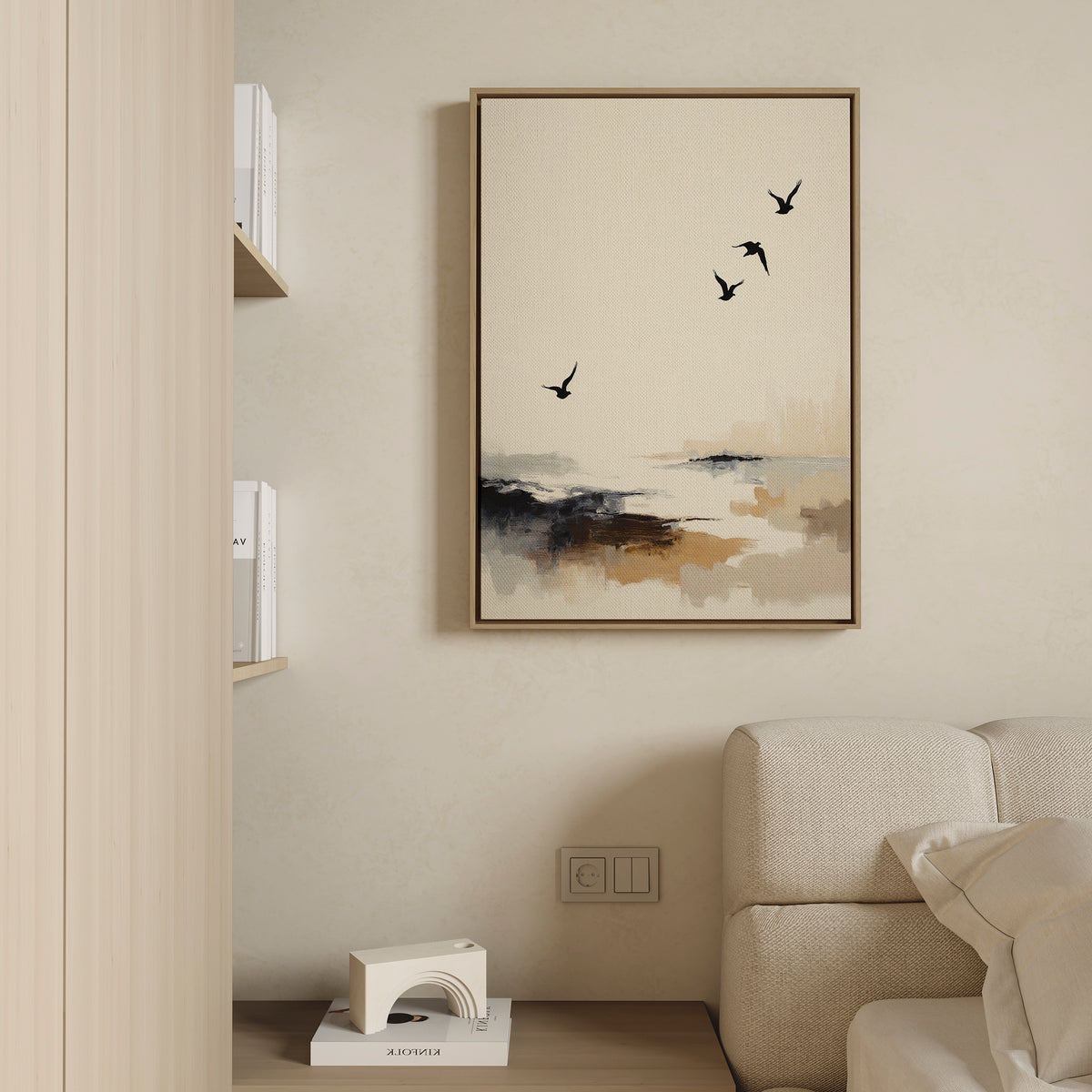 Minimalist living room with a beige sofa, coastal decor touches, the Maritime Flight Canvas Art - Vertical depicting birds over a misty seascape, a partial bookshelf, and a small white geometric sculpture on the lower shelf.