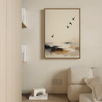 Minimalist living room with a beige sofa, coastal decor touches, the Maritime Flight Canvas Art - Vertical depicting birds over a misty seascape, a partial bookshelf, and a small white geometric sculpture on the lower shelf.