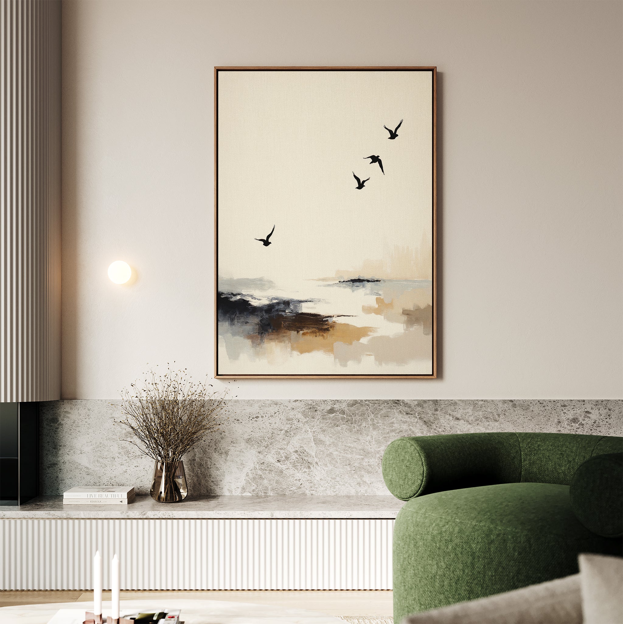 A modern living room with a green sofa and coastal decor showcases a built-in bench with marble detail. Above, the Maritime Flight Canvas Art - Vertical hangs, depicting an abstract seascape with four birds in flight. A vase with dried branches sits nearby.