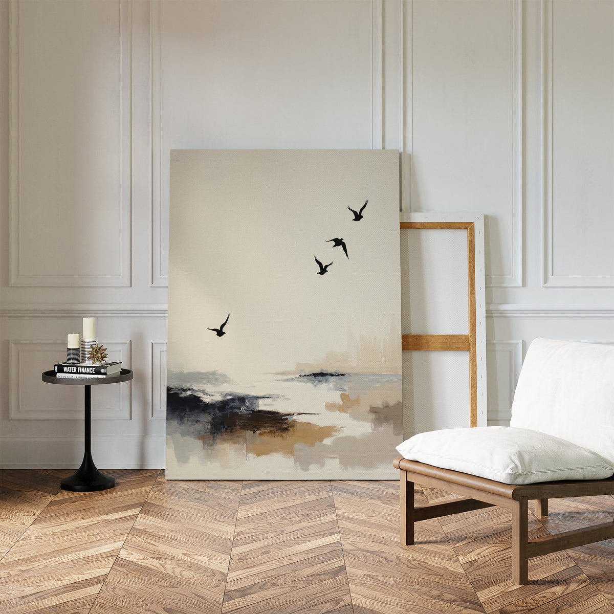 A modern room with herringbone wood flooring, a white cushioned chair, and a round side table displays coastal flair with the Maritime Flight Canvas Art - Vertical leaning against a white paneled wall beside an empty wooden frame.