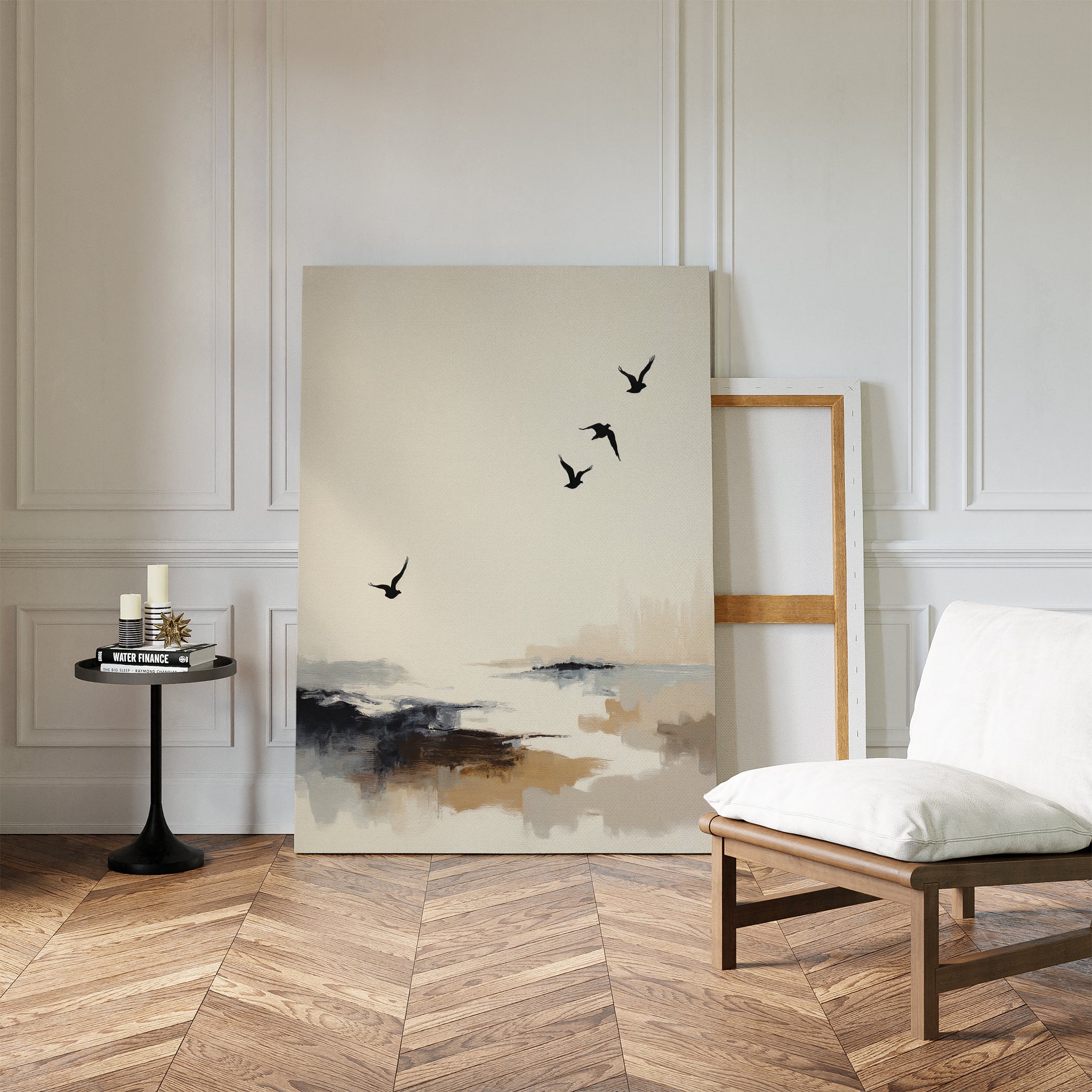 A modern room with herringbone wood flooring, a white cushioned chair, and a round side table displays coastal flair with the Maritime Flight Canvas Art - Vertical leaning against a white paneled wall beside an empty wooden frame.