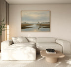 A modern living room features a light beige sectional sofa, a low wooden coffee table, and the Marsh Reflection Canvas Art - Horizontal above a calm water scene. Neutral, Nordic Park-inspired decor adds to the serene, minimalistic atmosphere.
