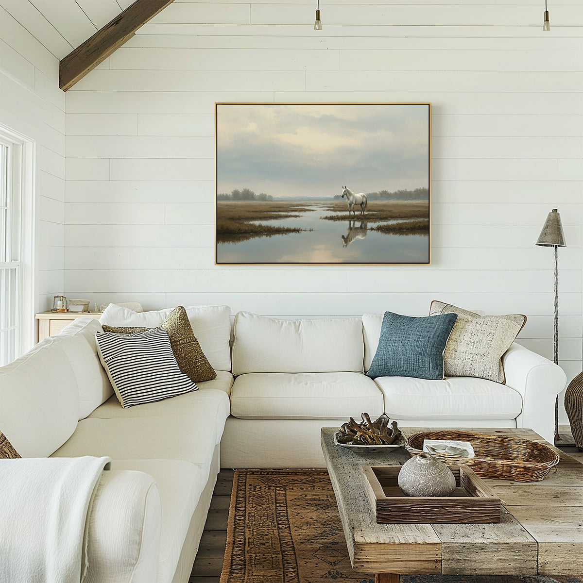 A cozy white shiplap living room features a large sectional sofa, rustic wooden coffee table, woven baskets, and pillows. Above the sofa hangs the Marsh Reflection Canvas Art - Horizontal for a serene touch.