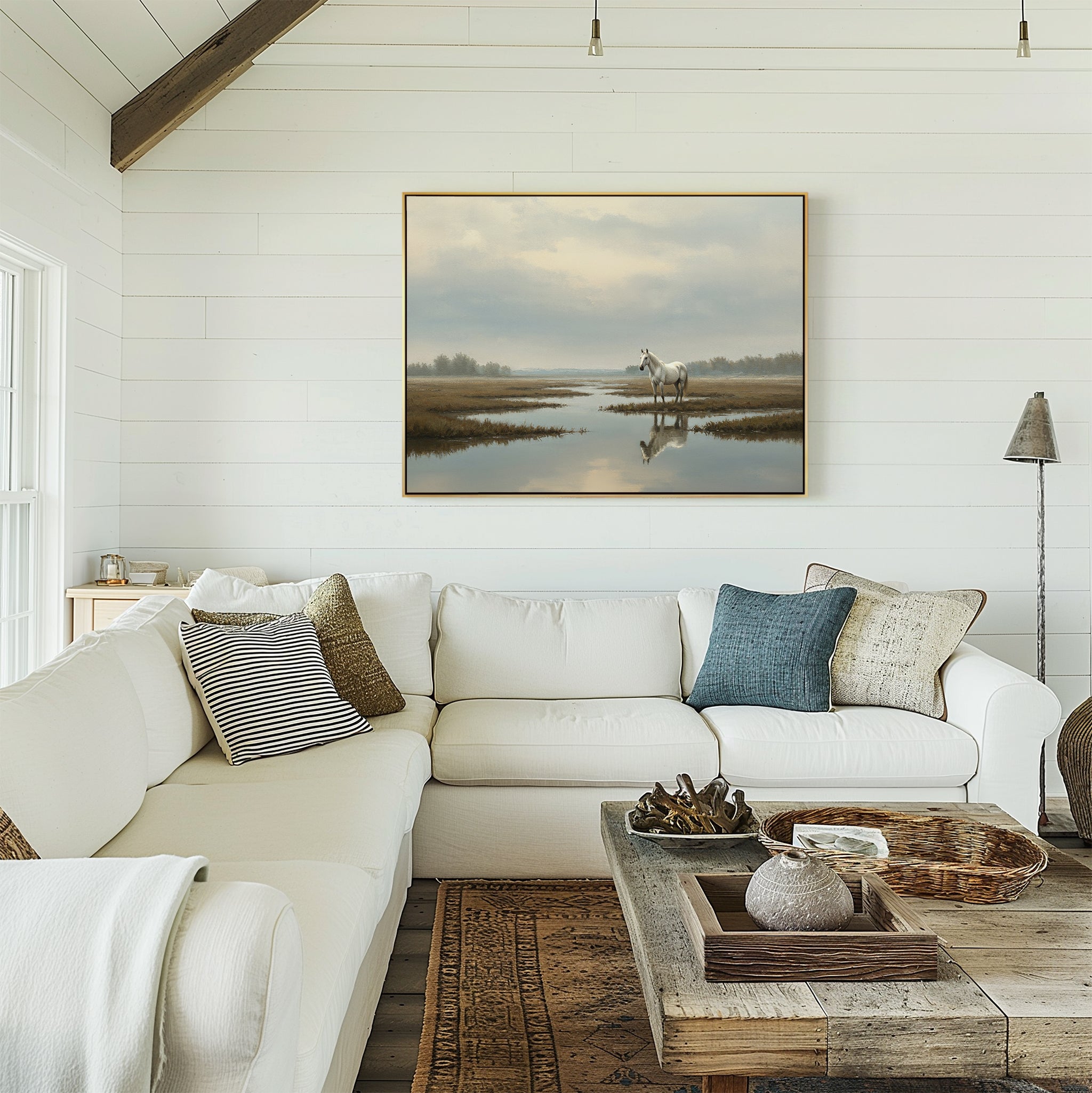 A cozy white shiplap living room features a large sectional sofa, rustic wooden coffee table, woven baskets, and pillows. Above the sofa hangs the Marsh Reflection Canvas Art - Horizontal for a serene touch.