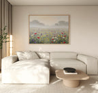 A modern living room features a cream sectional, light wood coffee table, tall plant, and the Meadow Dreams Canvas Art - Horizontal depicting a foggy meadow above the sofa. Neutral tones and soft natural light enhance the calm atmosphere.