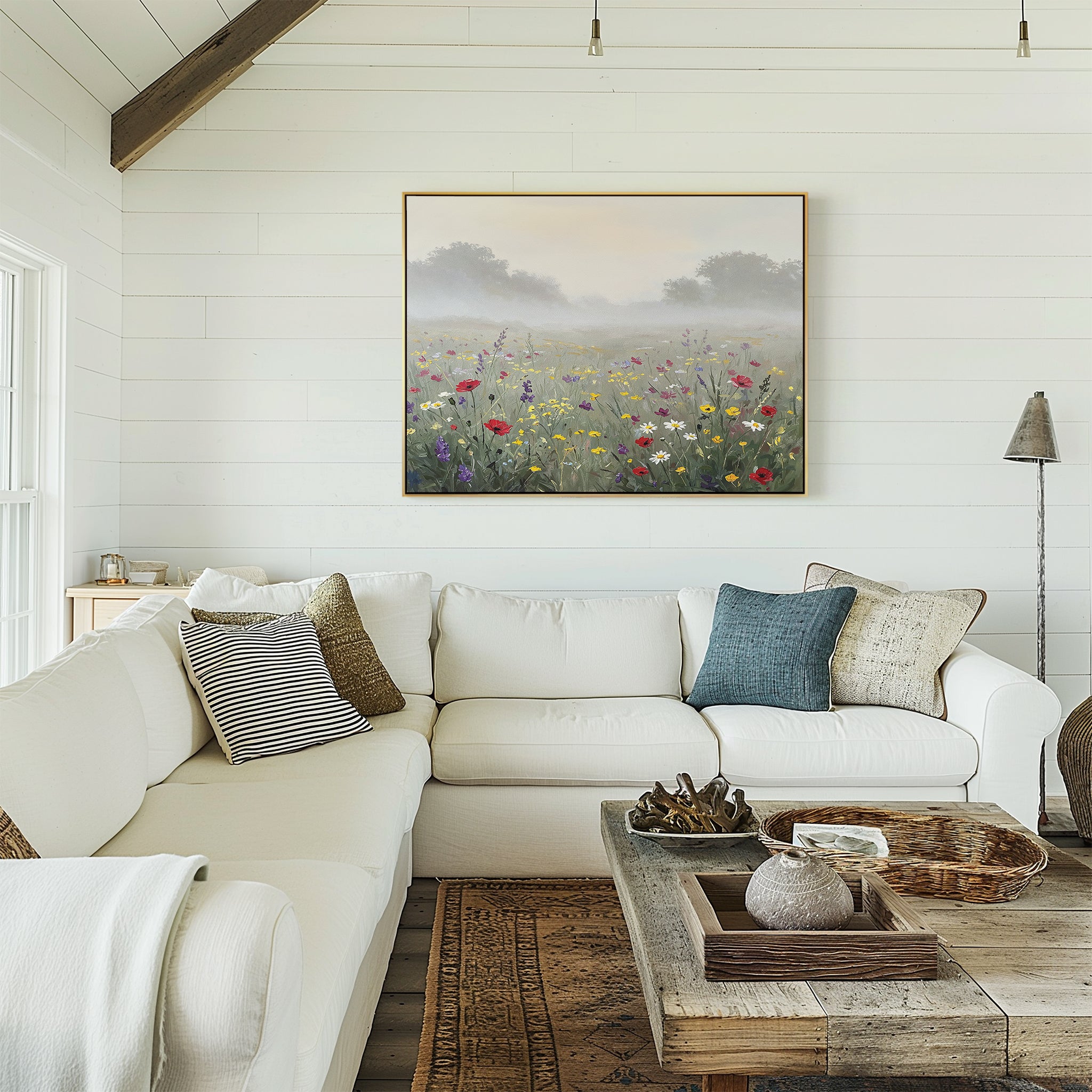 A cozy living room with a white sectional sofa, assorted cushions, a rustic wooden coffee table, and the Meadow Dreams Canvas Art - Horizontal featuring a misty meadow hanging on the shiplap wall.