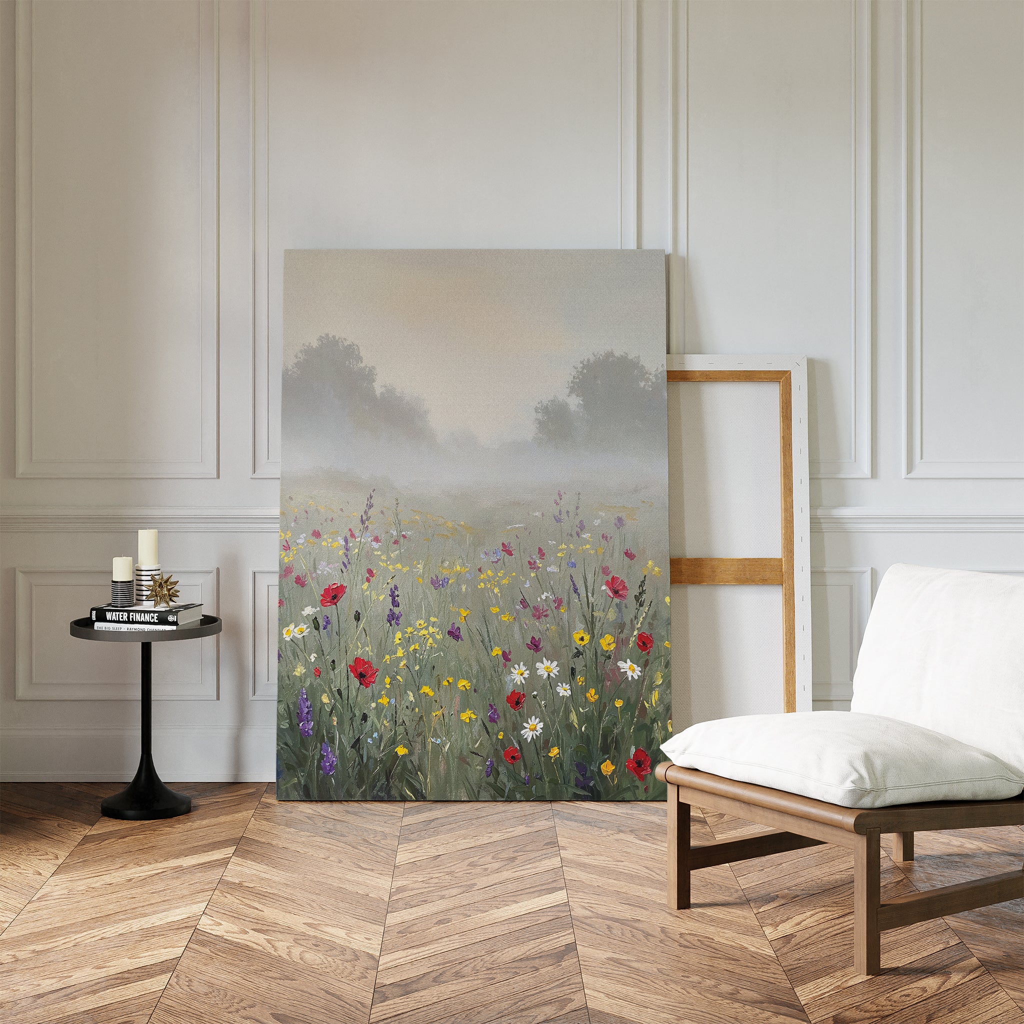 The Meadow Dreams Canvas Art - Vertical, depicting a wildflower meadow, leans against a white-paneled wall in a bright room with parquet flooring, a cushioned chair, and a small round table with candles and books.