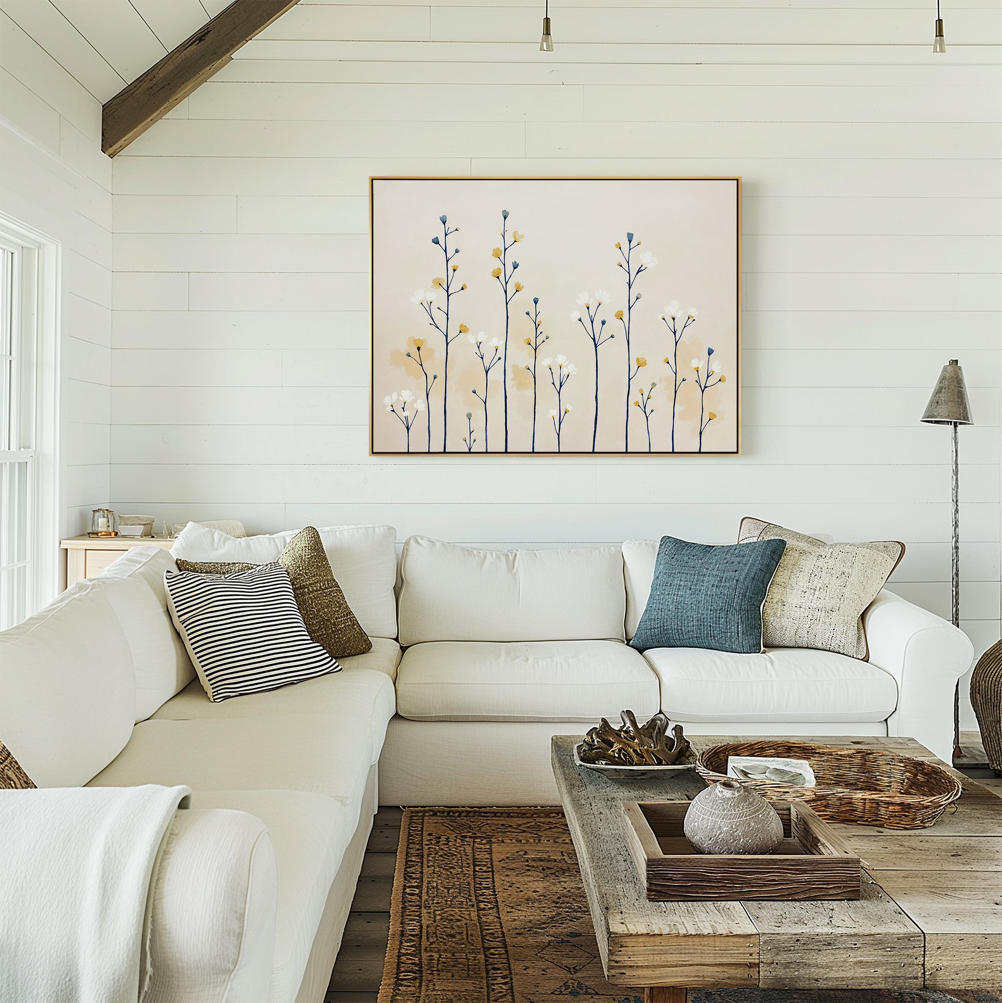 A cozy living room with a white sectional sofa, textured pillows, a rustic coffee table, and the Meadow Symphony Canvas Art - Horizontal featuring botanical silhouettes. White shiplap walls and natural accents complete the space.
