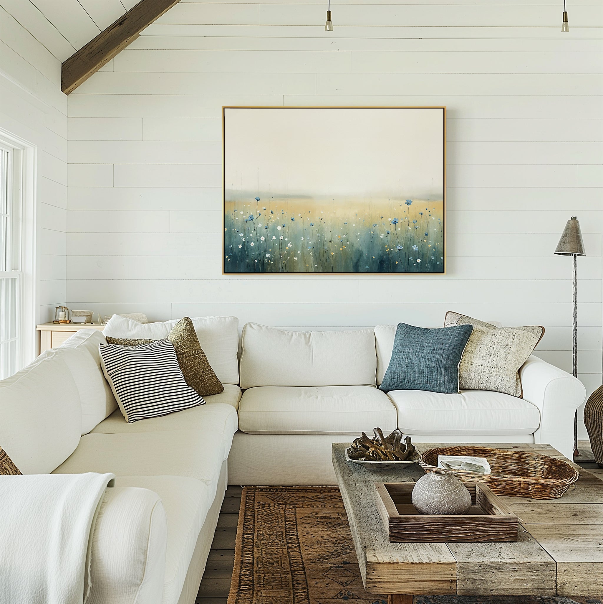 A cozy living room with a white sectional sofa, assorted throw pillows, a rustic wooden coffee table, and the Meadow Whispers Canvas Art - Horizontal on the shiplap wall creates a serene and inviting atmosphere.