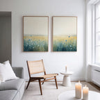 A modern living room with a light gray sofa, wooden chair with woven seat, small round white table, and lit candles. Above the chair, two large Meadow Whispers - Set of 2 canvas prints adorn the white wall.