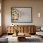 A cozy living room features a wooden sideboard, light wood coffee table, beige sofa, and the Mediterranean Dreams Canvas Art - Horizontal above the sideboard; a vase of flowers on the coffee table completes the serene decor.
