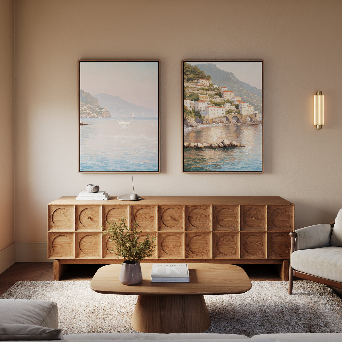 A cozy living room featuring the Mediterranean Dreams - Set of 2 wall art, a wooden sideboard, round coffee table with vase and book, light armchair, and textured rug for a serene home decor look.