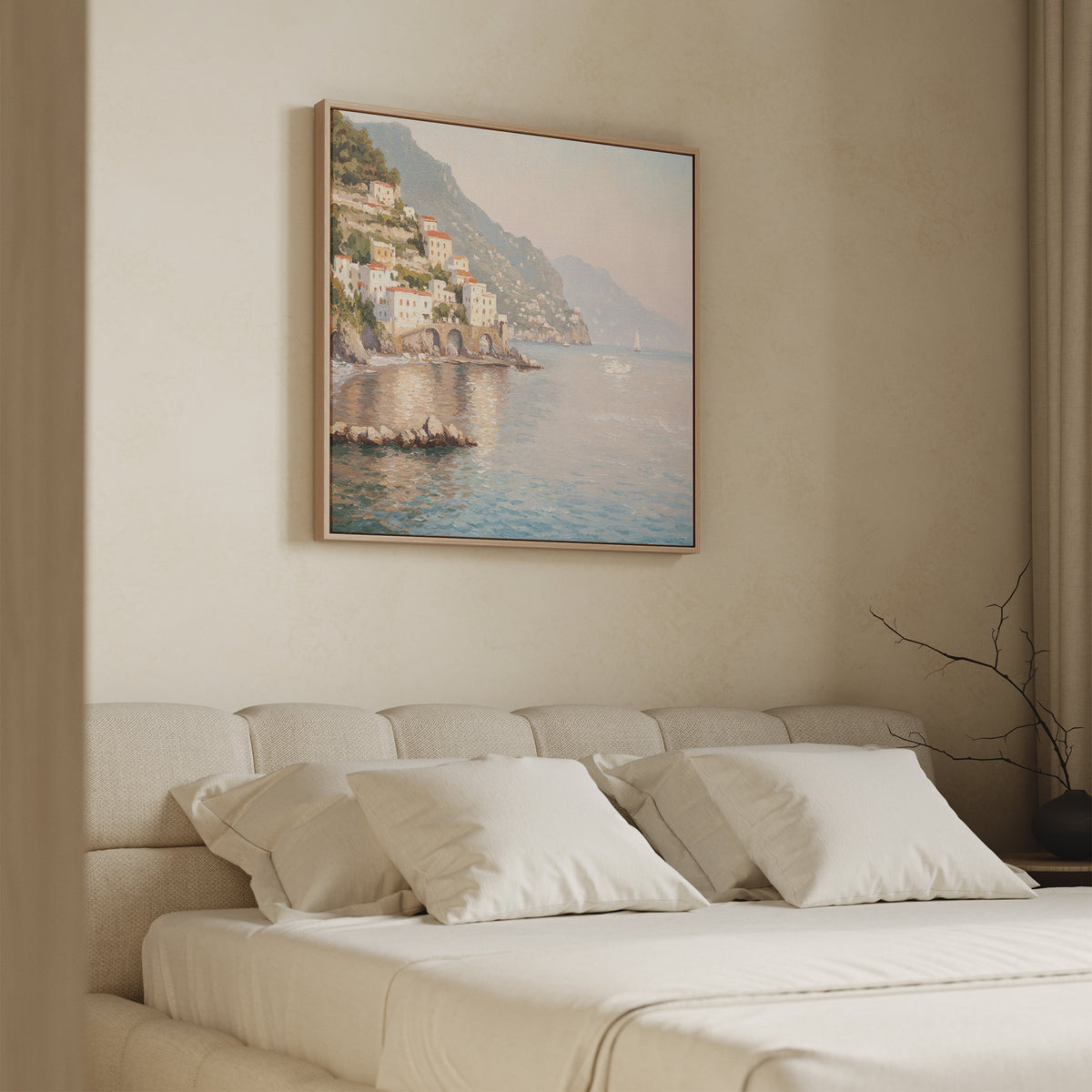 A minimal, modern bedroom features a beige bed, white pillows, and the Mediterranean Dreams Canvas Art - Square of a coastal village above the headboard. Soft natural light filters through a curtain on the right, enhancing the serene home decor.